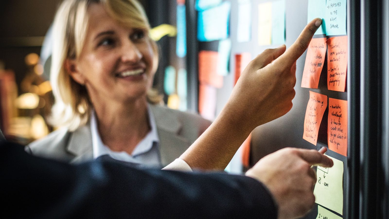 A woman looks at a series of sticky notes describing blockchain EAM lessons learned